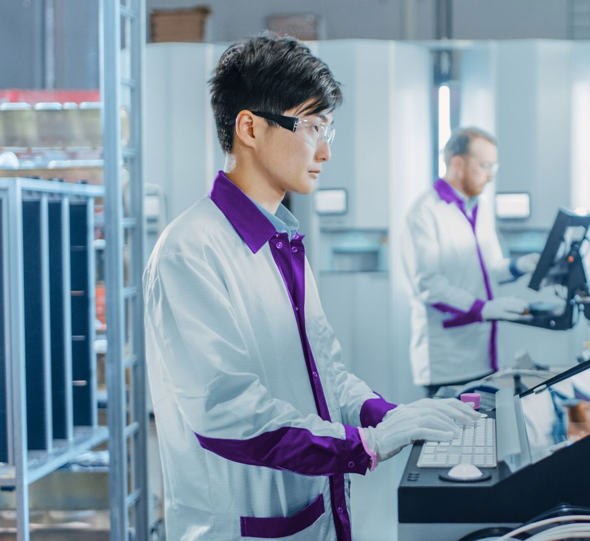 Scientist in lab coat typing into computer in computer lab