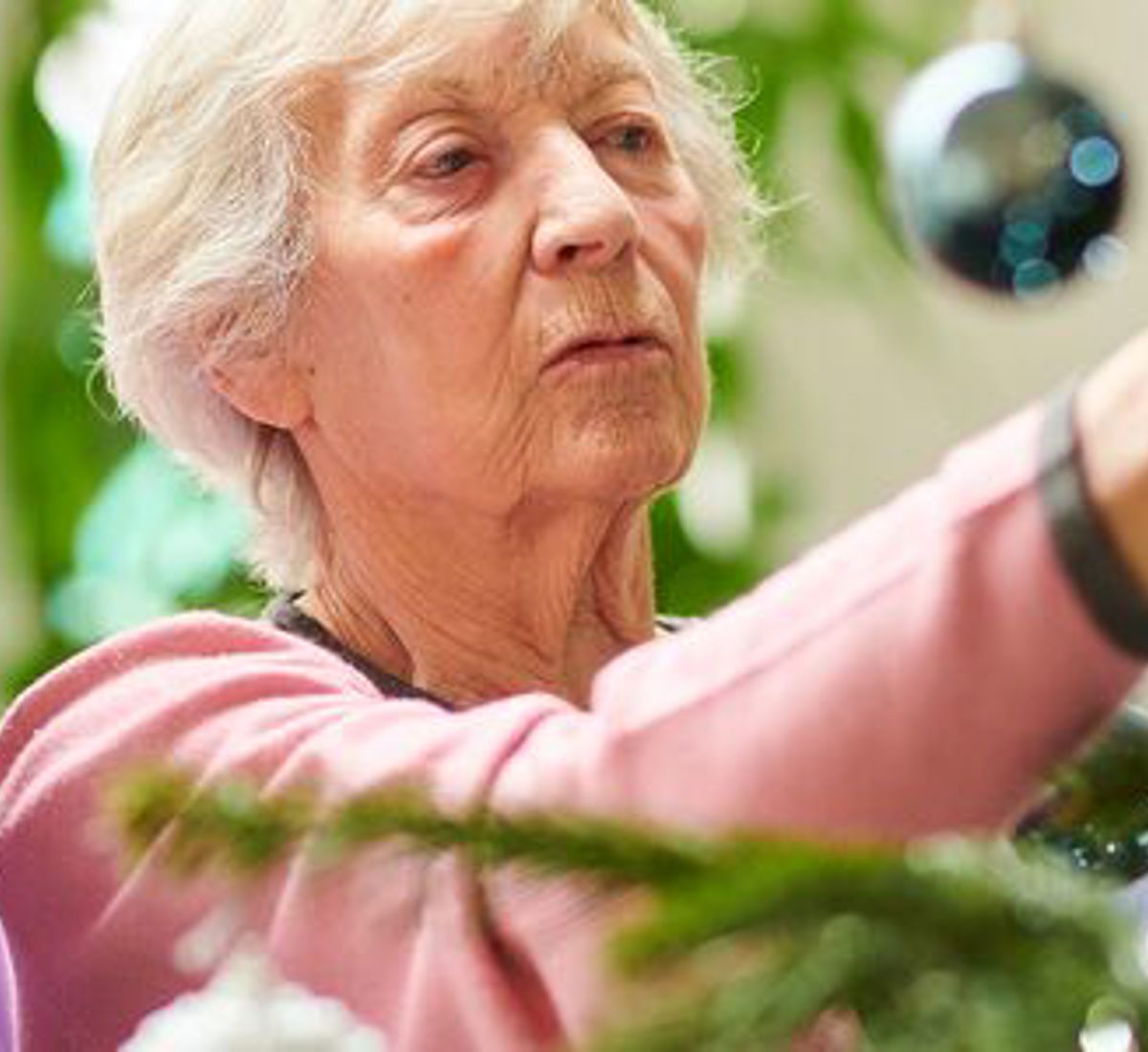 A healthcare worker during the holidays helping a patient decorate a tree